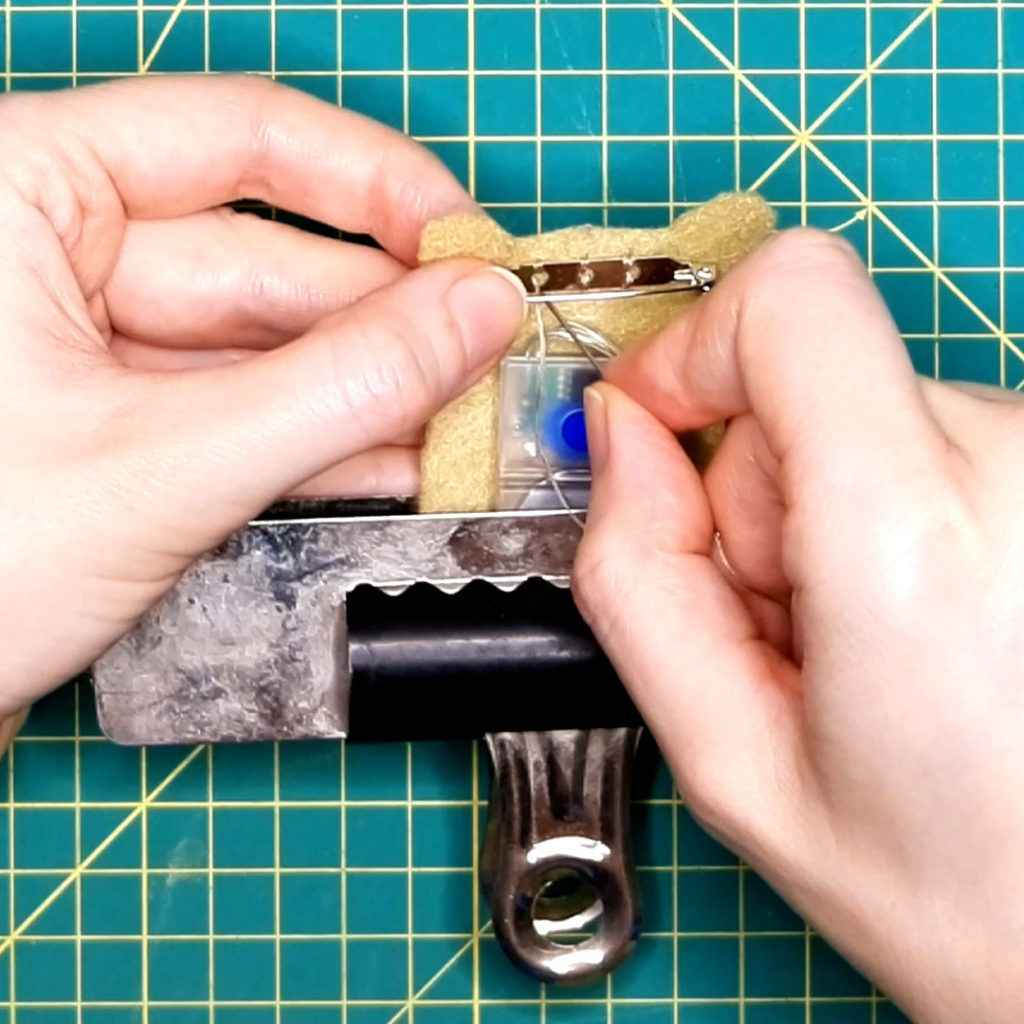 the brooch backing is being sewn onto the back of the reindeer head piece