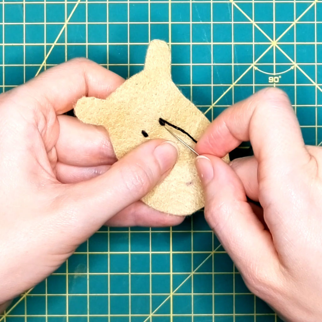 the eyes are being darned into the reindeer face felt piece using embroidery thread